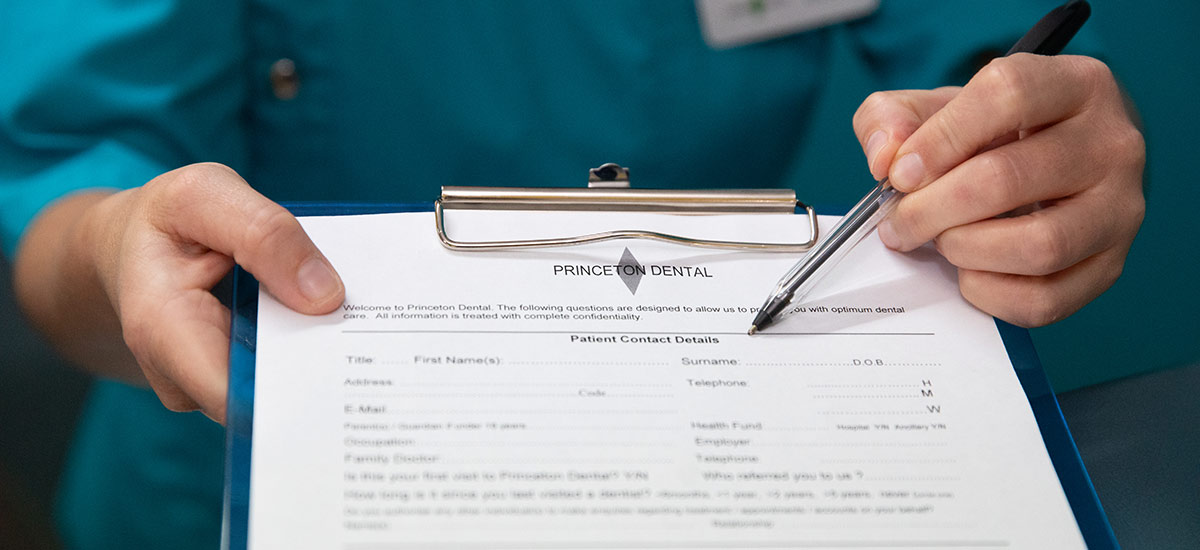Dental team member handing over a Princeton Dental new patient form